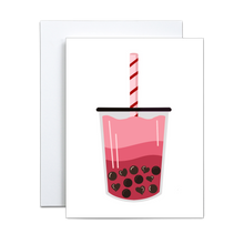 Load image into Gallery viewer, graphic design illustration of boba milk tea where the liquid is gradient shades of pink and the boba are heart shaped and regular shaped in a cup with a black lid and a light pink straw with red stripes on a white background greeting card