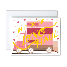 Load image into Gallery viewer, pink, dark pink, and shades of brown moving van with boxes ready to load and pink hearts with yellow 'in it for the long haul' script text over the front greeting card