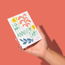 Load image into Gallery viewer, hand holding yellow, salmon, light green, blue, and light pink floral shapes with light green text saying &#39;happy anniversary&#39; on white background greeting card
