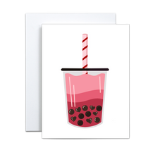 Load image into Gallery viewer, graphic design illustration of boba milk tea where the liquid is gradient shades of pink and the boba are heart shaped and regular shaped in a cup with a black lid and a light pink straw with red stripes on a white background greeting card
