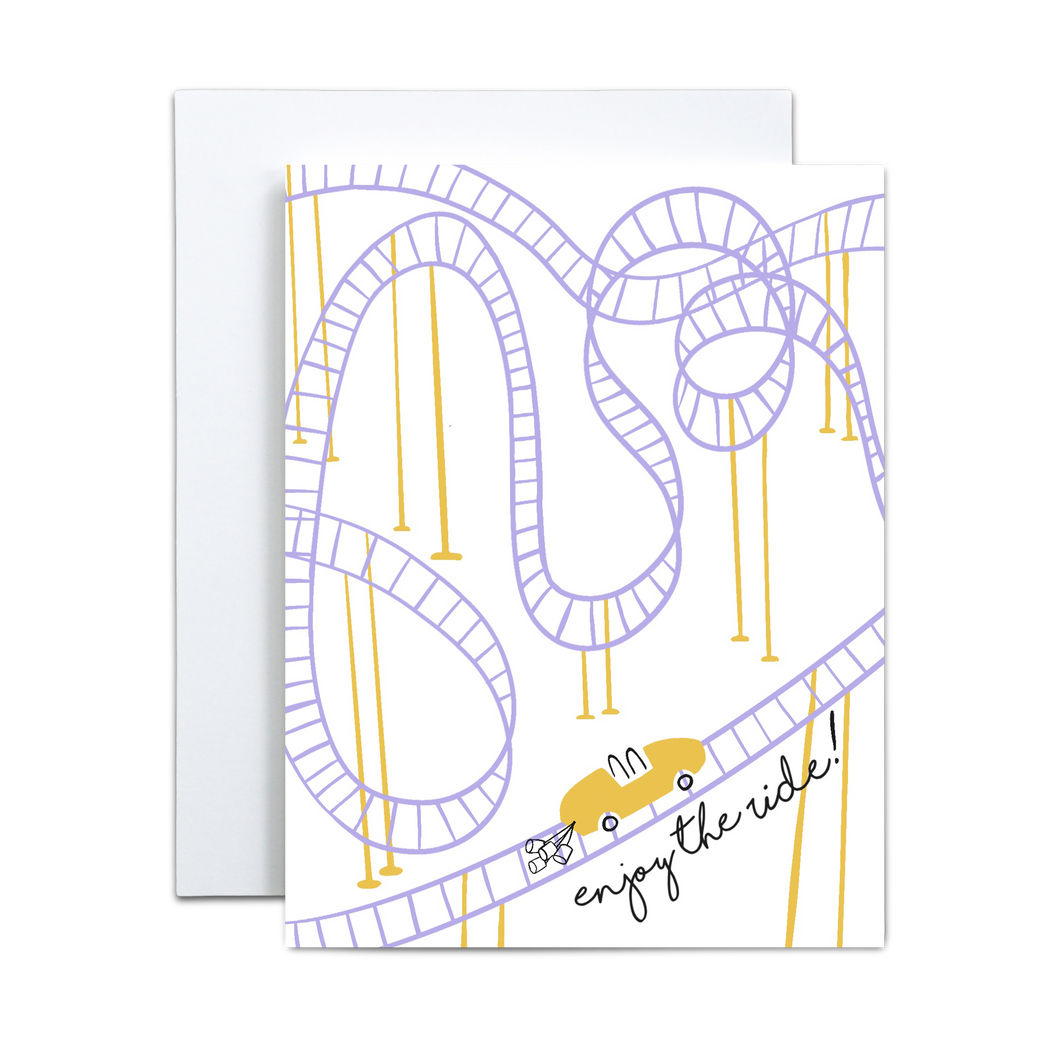 linework based illustration of a purple and yellow rollercoaster with a yellow cart with two shapes and wedding cans trailing off the back with 'enjoy the ride' along the bottom greeting card